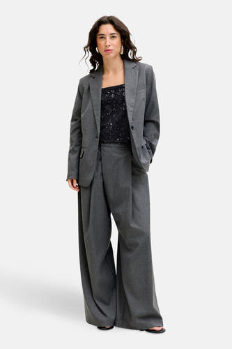 Blouse no manches noire JJXX avec motif floral et un pantalon gris.