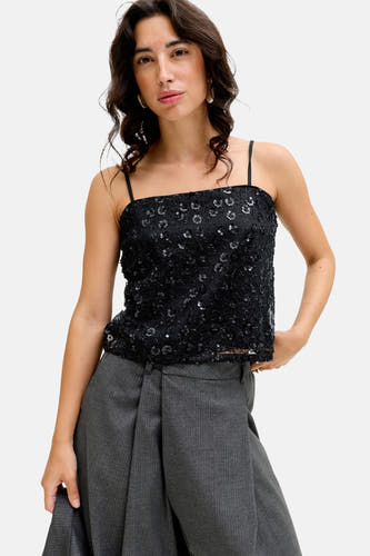 Blouse sans manches noire de JJXX, ornée de strass, associée à un pantalon gris.