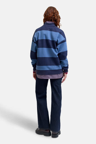 Pull-over bleu de JJXX avec des rayures horizontales, porté sur un chemisier à carreaux et des jeans foncés et des chaussures grossières, dos.