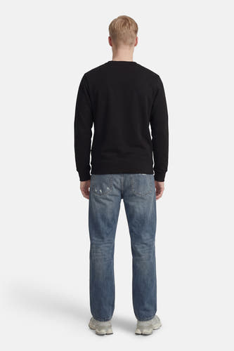 Pull noir de CORE BY JACK & JONES, à manches longues, porté avec un jean bleu et des baskets grises, vue arrière.