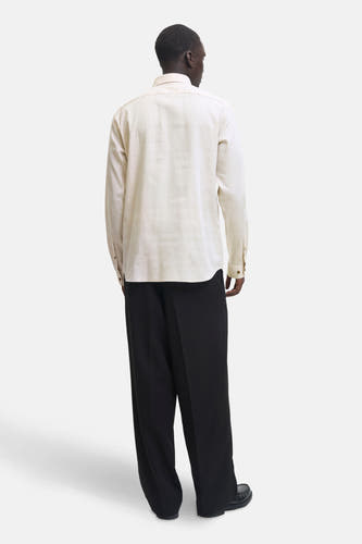 Chemise beige à manches longues de PREMIUM by JACK & JONES, vue de derrière, associée à un pantalon noir et des chaussures.