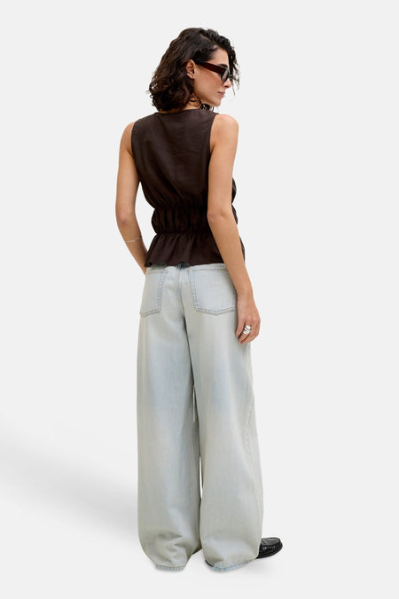 Chemisier sans manches marron de JJXX avec ourlet péplum et taille élastique, associé à un jean ample bleu clair, vu de dos.