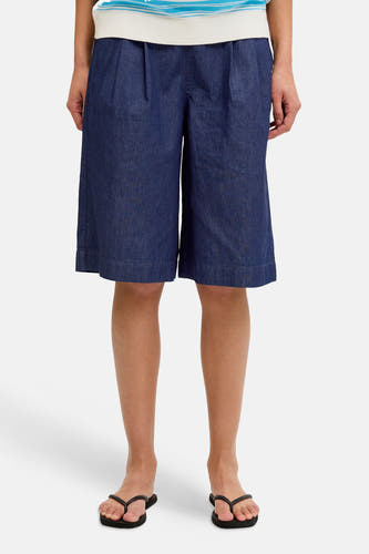 Short en jean bleu marine JJXX à jambes larges et plis, porté avec un polo rayé et des tongs.