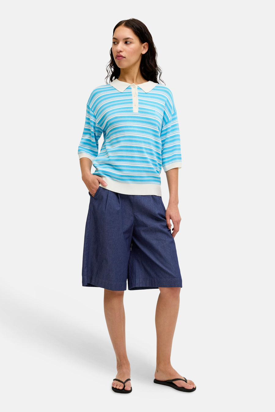 Donkerblauwe denim shorts van JJXX met wijde pijpen en plooien, gedragen met gestreepte polo en teenslippers.