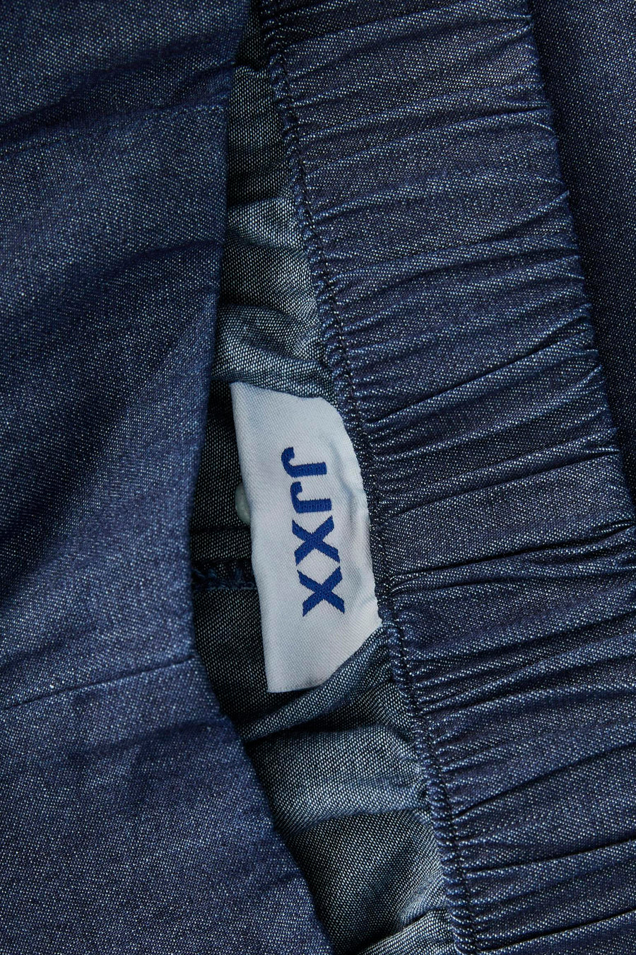 Short en jean bleu marine de JJXX, avec détail de taille froncée et une étiquette blanche de la marque.