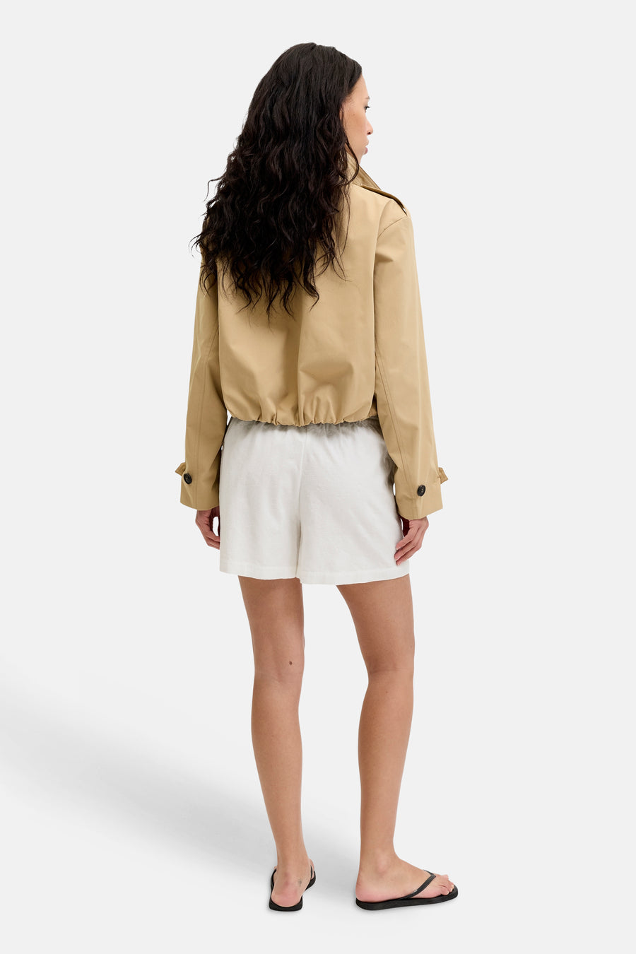 Short blanc JJXX texturé, porté avec une veste beige et des tongs noires, vu de dos.
