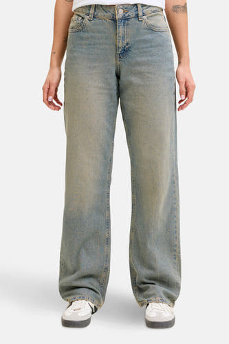 Jean bleu moyen droit en denim de JJXX, avec des coutures visibles et un effet porté, associé à des baskets blanches.