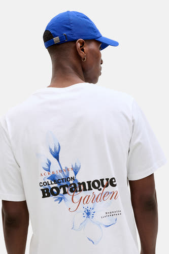 T-shirt blanc de ORIGINALS BY JACK & JONES, avec un imprimé botanique au dos et porté avec une casquette bleue.