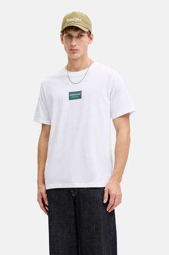 T-shirt blanc à manches courtes de CORE by JACK & JONES, avec logo sur la poitrine, associé à une casquette et un jean foncé.