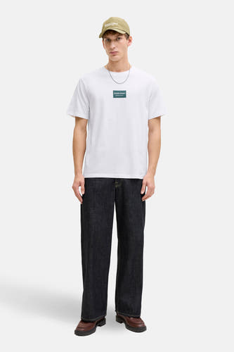 Wit T-shirt met korte mouwen van CORE by JACK & JONES, met logo op de borst, gecombineerd met een pet en donkere jeans.