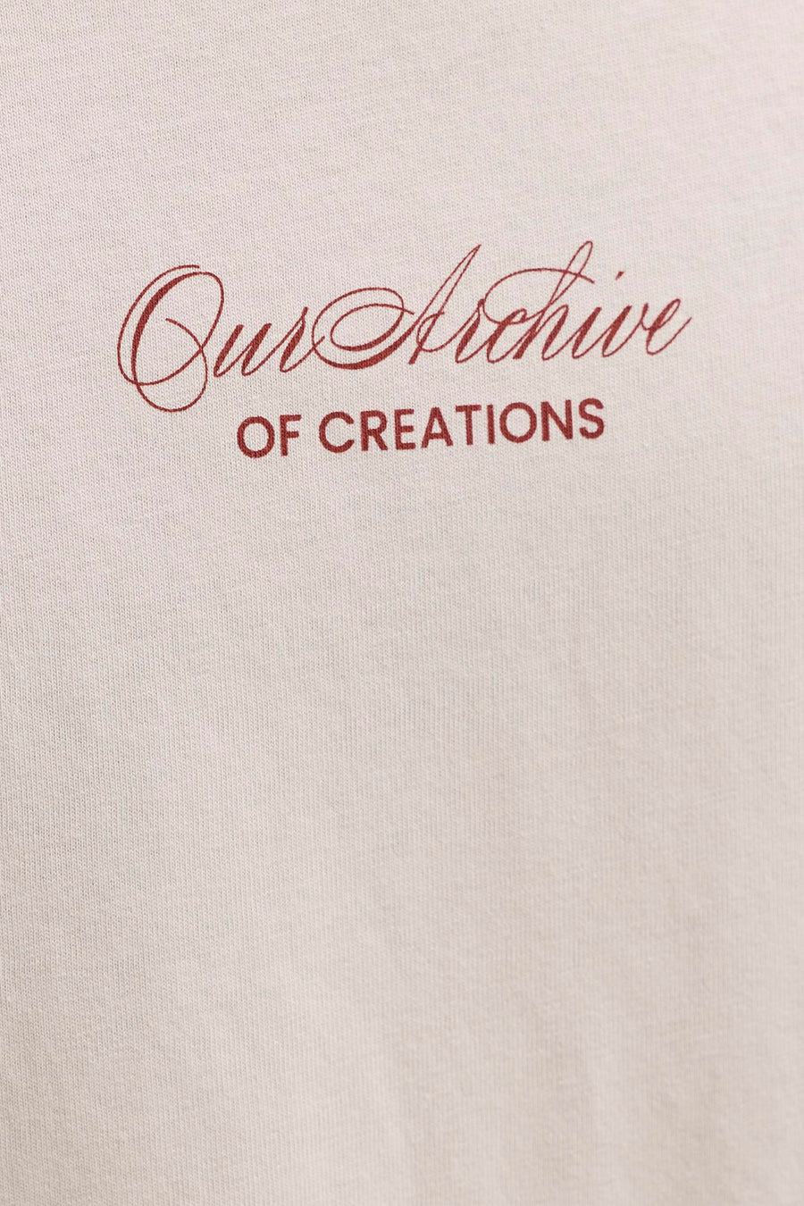 T-shirt beige de ORIGINALS BY JACK & JONES avec texte rouge 'Our Archive OF CREATIONS' sur un tissu tricoté.