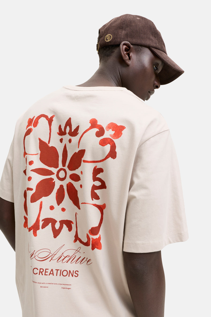 T-shirt beige de ORIGINALS BY JACK & JONES, vu de dos, avec un grand imprimé floral rouge et du texte dans le dos.