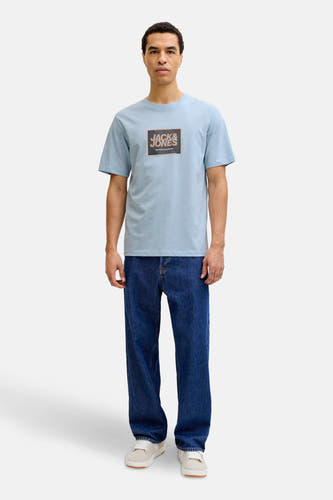 Blauw T-shirt met korte mouwen van Originals by Jack & Jones, met logo op de borst, gecombineerd met blauwe jeans en witte sneakers.