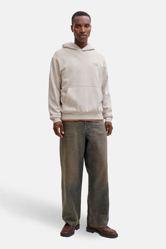 Pull-over beige avec capuche d'ORIGINALS BY JACK & JONES, porté sur un t-shirt orange et des jeans larges foncés.