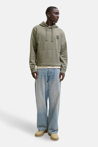 Gilet kaki avec col d'ORIGINALS BY JACK & JONES, logo sur la poitrine, associé à un jeans large et des chaussures en cuir de mouton.