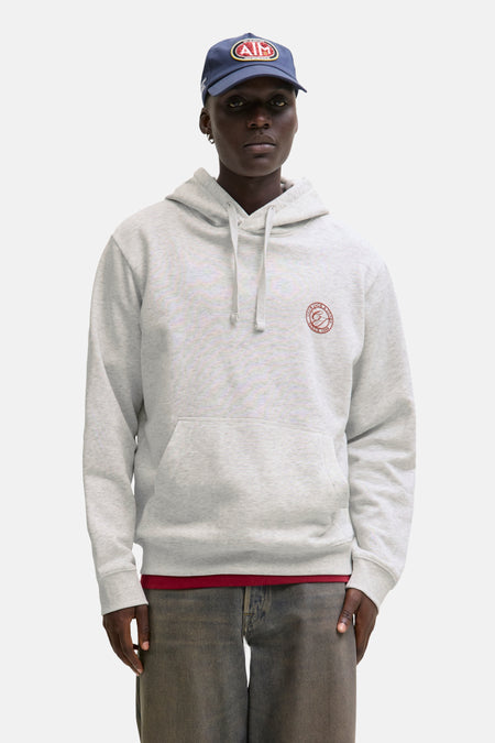 Een man met een blauwe pet en grijze hoodie met een logo.