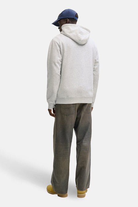 Man met pet, grijze hoodie, wijde broek en gele schoenen.