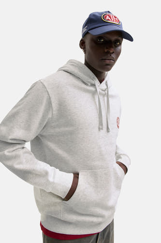 Pull-over blanc avec capuche d'ORIGINALS BY JACK & JONES, avec des cordons de serrage et une poche kangourou, porté avec un chapeau.