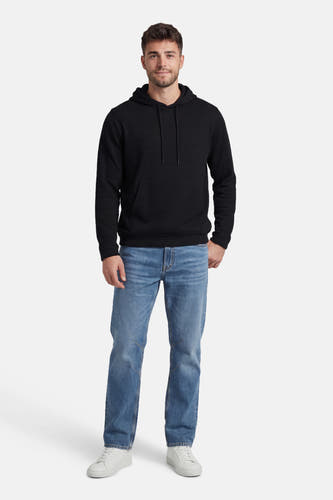 Zwarte sweater met kap van CORE BY JACK & JONES, gecombineerd met blauwe jeans en witte sneakers.