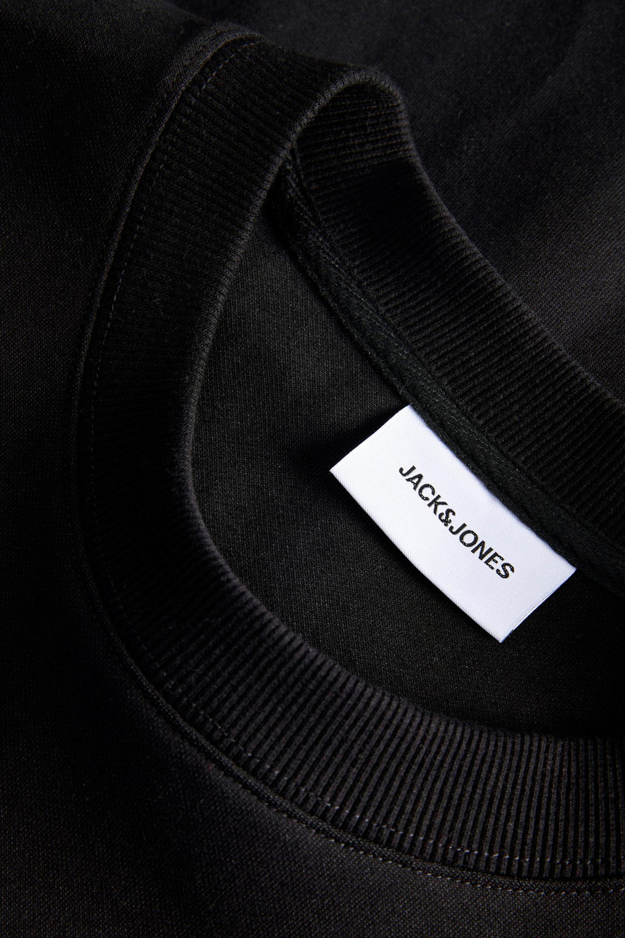 Zwarte sweater van CORE BY JACK & JONES, met geribbelde kraag en een wit label zichtbaar.
