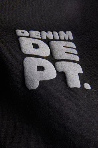 Pull noir de CORE BY JACK & JONES, avec un imprimé texte en relief sur le devant.