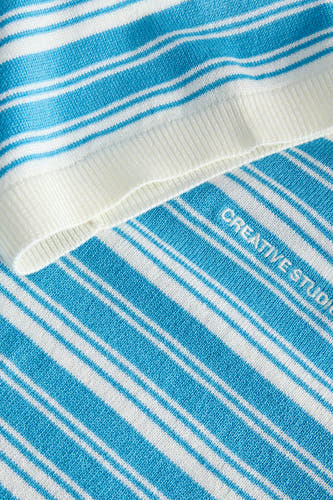 Pull bleu de JJXX, avec des rayures blanches et le texte "CREATIVE STUDIO" imprimé en diagonale.