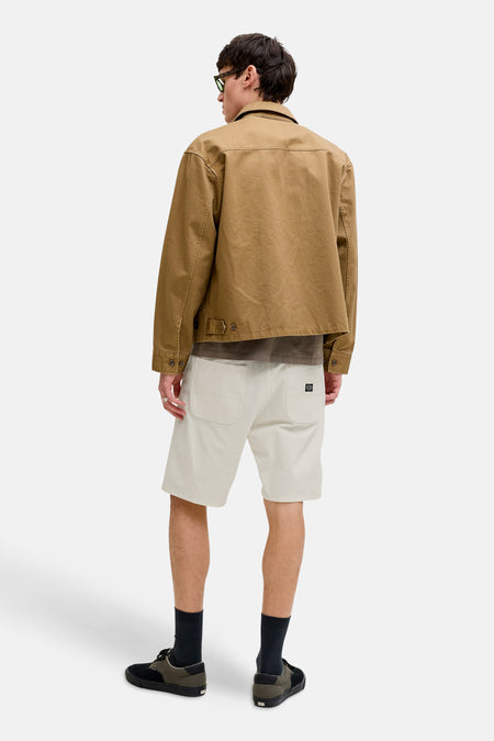 Short beige de JACK & JONES JEANS INTELLIGENCE, avec poches arrière et une étiquette de marque, combiné avec une veste marron et des chaussettes noires.