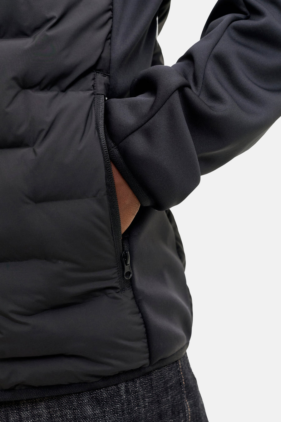 Zwart donsjack met ritszak en donkere jeans.