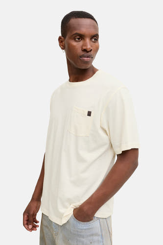 T-shirt beige à manches courtes de PREMIUM by JACK & JONES, avec poche poitrine et porté avec un jean.