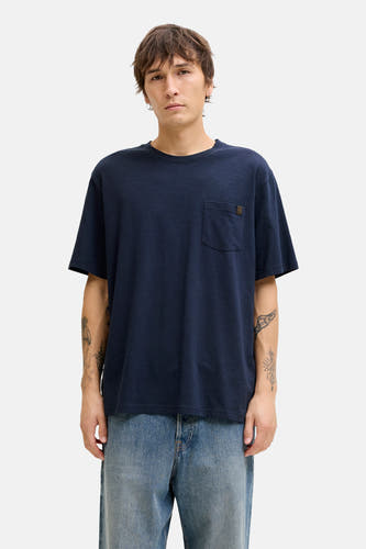 T-shirt bleu à manches courtes de PREMIUM by JACK & JONES, avec poche poitrine, porté avec un jean décontracté et des chaussures marron.