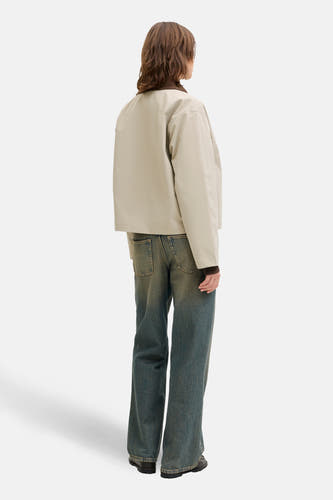 Manteau court beige de JJXX, avec une collier marron et porté avec des jeans bleus larges et des chaussures noires.