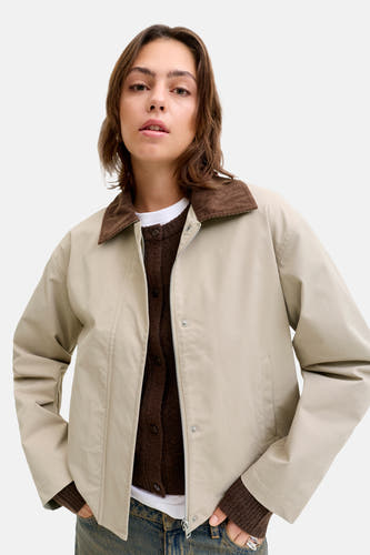 Manteau beige court de JJXX, avec une collet marron et porté sur un gilet marron et un T-shirt blanc.