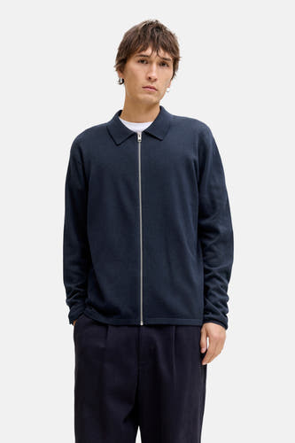 Gilet bleu d'ORIGINALS BY JACK & JONES, avec une fermeture éclair argentée, porté sur un T-shirt blanc et un pantalon bleu marine avec des chaussures marron.