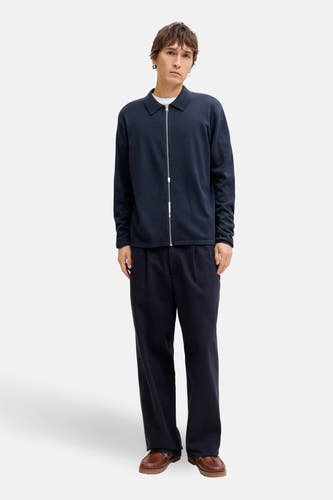 Blauw gilet van ORIGINALS BY JACK & JONES, met een zilveren ritssluiting, gedragen over een wit T-shirt en een donkerblauwe pantalon met bruine schoenen.
