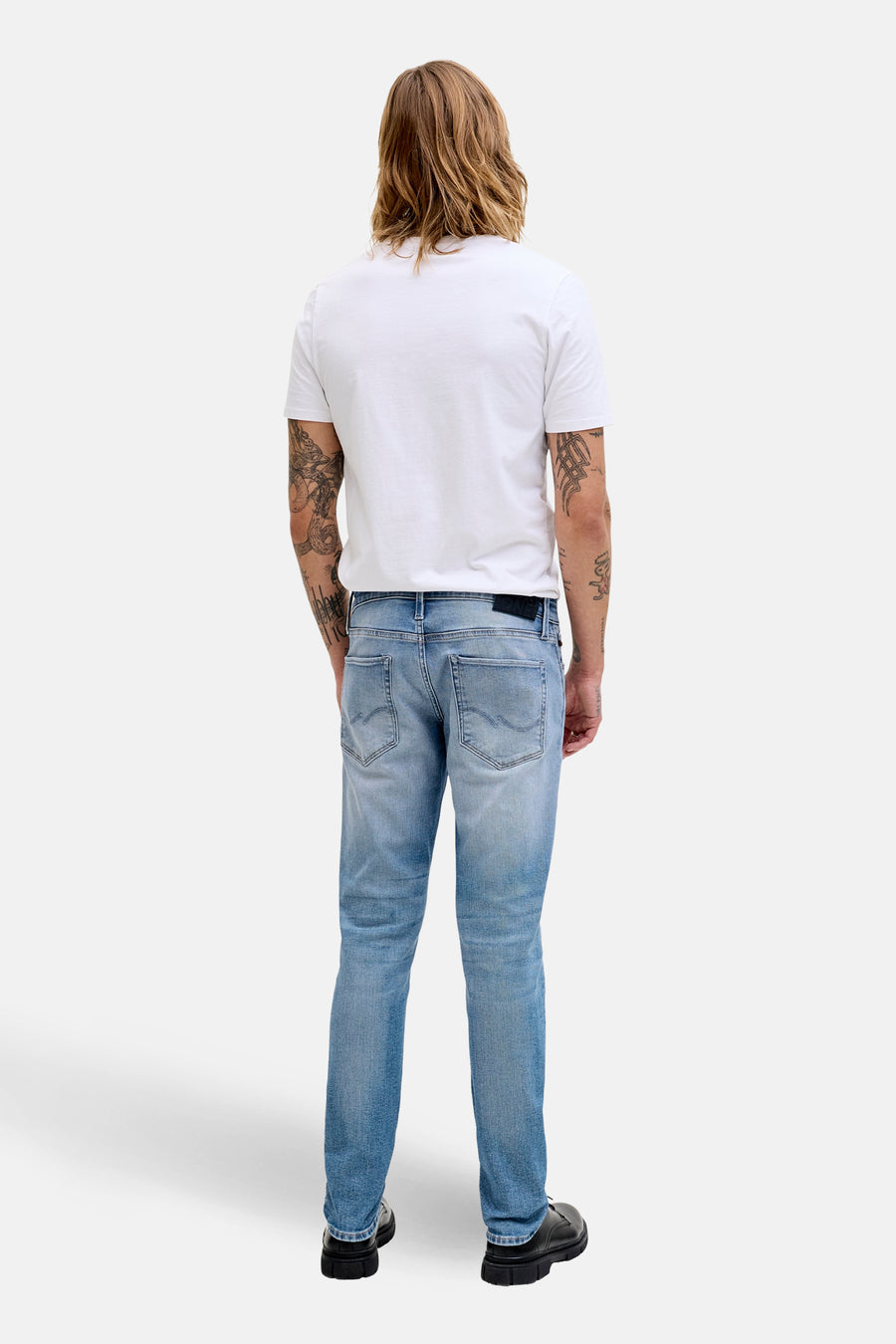 Jean slim fit en denim bleu clair de JACK & JONES, avec des tatouages sur les bras.