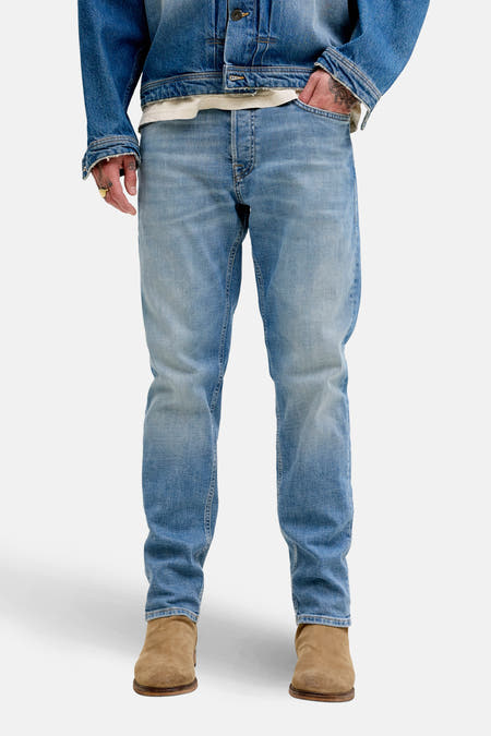 Taps toelopende jeans van denim in middenblauw door JACK & JONES JEANS INTELLIGENCE, met licht verwassen effect en bruine laarzen.