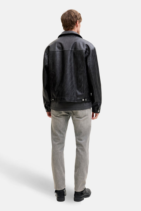 Man van achteren in een zwarte leren jas en grijze jeans.