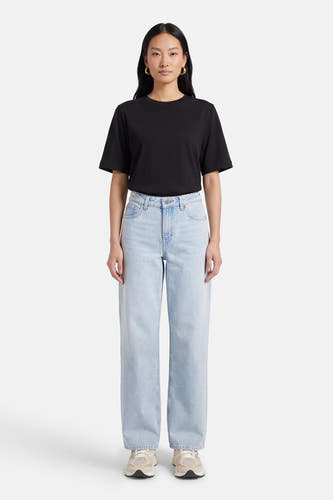 Lichtblauwe straight jeans van JJXX, gedragen met een zwart T-shirt en crèmekleurige sneakers.

