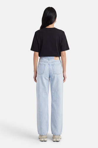 Jean droit en denim bleu clair de JJXX, vu de dos, avec un t-shirt noir et des baskets couleur crème.
