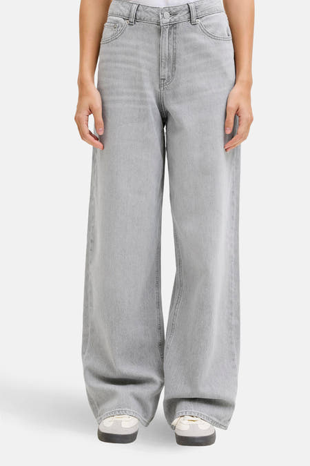 Jean en denim gris large de JJXX, associé à un T-shirt blanc et des baskets.