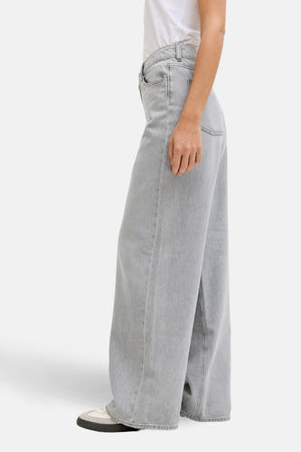 Jean clair gris, large de JJXX, avec une texture denim, porté avec un T-shirt blanc et des baskets, en vue latérale.