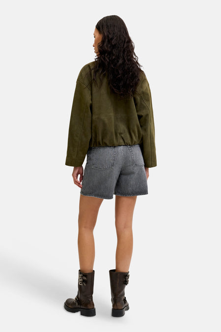 Short en jean gris foncé de JJXX avec ourlets effilochés, vu de dos, porté avec une veste en daim vert et des bottes marron.
