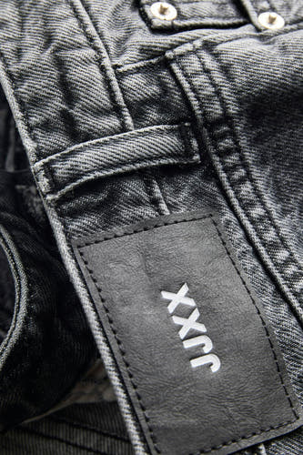 Short en jean gris foncé de JJXX avec étiquette en cuir noir, logo blanc et boutons apparents.