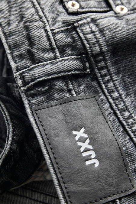 Short en jean gris foncé de JJXX avec étiquette en cuir noir, logo blanc et boutons apparents.