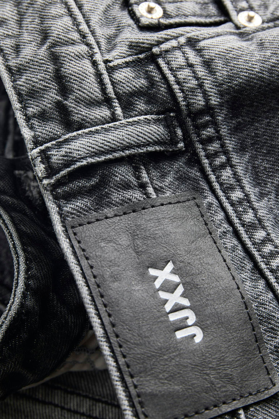 Short en jean gris foncé de JJXX avec étiquette en cuir noir, logo blanc et boutons apparents.