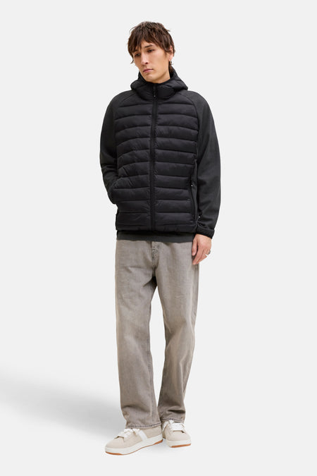 Man met zwarte gewatteerde jas, grijze broek en witte sneakers.