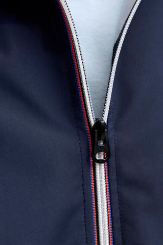 Manteau court bleu d'ORIGINALS BY JACK & JONES, avec une fermeture éclair blanche et une bande rouge et bleue le long de la fermeture éclair.
