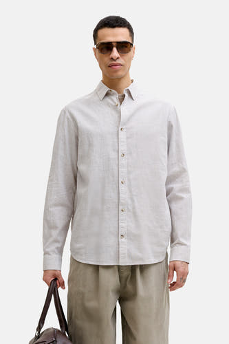 Chemise beige à manches longues de PREMIUM by JACK & JONES, portée avec une veste marron et un sac de la même couleur.