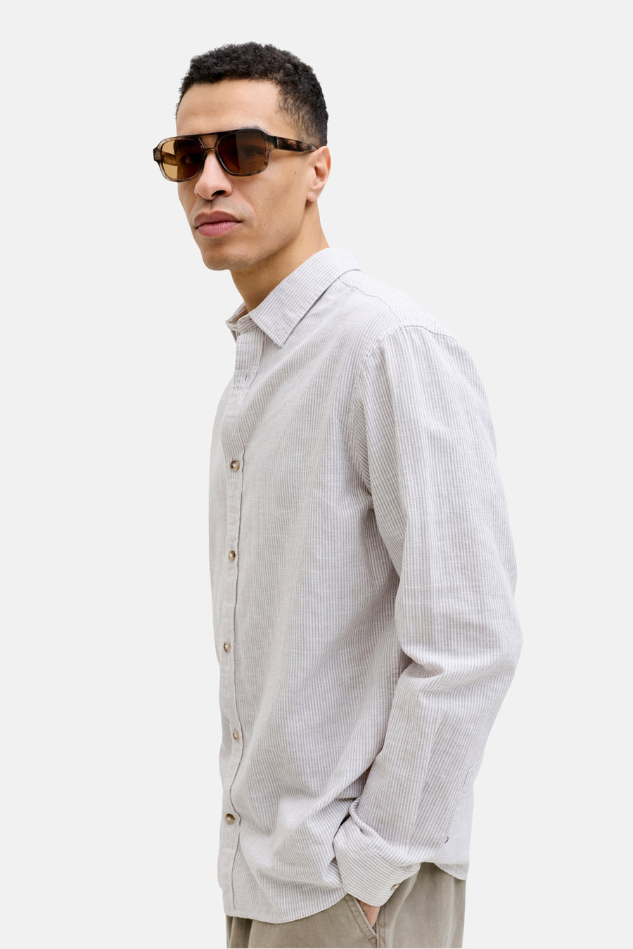 Chemise beige à rayures de PREMIUM by JACK & JONES, à manches longues et fermeture boutonnée, portée avec un pantalon kaki et des lunettes de soleil marron.