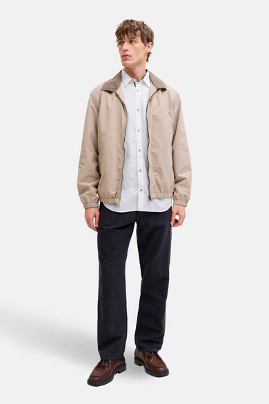 Wit overhemd met lange mouwen van PREMIUM by JACK & JONES, gedragen met een beige jack, zwarte broek en bruine schoenen.